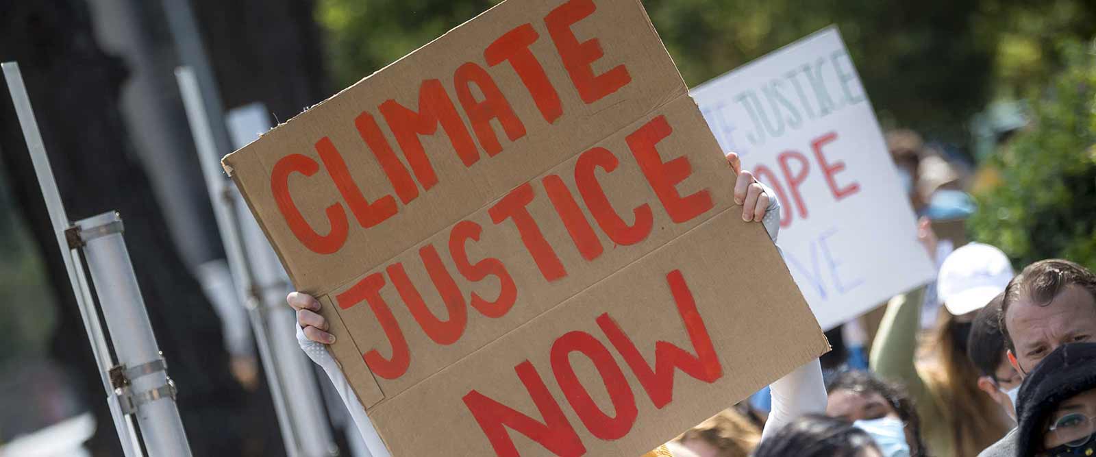 Photo of protester at UC San Diego climate march with climate justice sign.